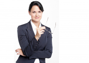 Eine Frau, die Seriös im Anzug in die Kamera schaut.