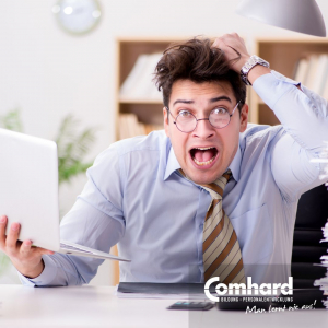 Ein Mann fasst sich an den Kopf und schaut überfordert in die Kamera, In der linken Hand hält er einen Laptop.