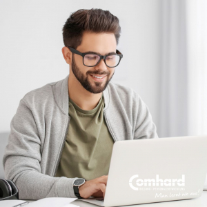 Ein Mann sitzt vor einem Laptop und lächelt.