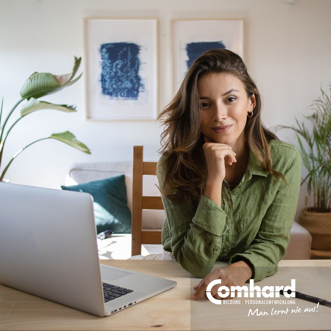 Eine Frau schaut freundlich in die Kamera. Neben ihr steht ein Laptop