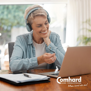 Eine Frau sitzt lächelnd vor einem Laptop. Sie trägt Kopfhörer.