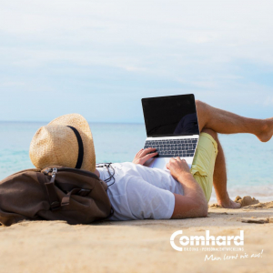 Ein Mann liegt an einem Strand und hat einen Laptop auf seinem Schoß