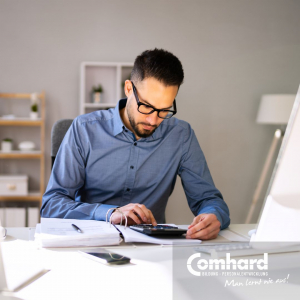 Ein Mann sitzt konzentriert an einem Tisch und rechnet mit einem Taschenrechner.