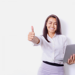 Eine Frau zeigt stolz einen Daumen hoch und grinst in die Kamera. In der andren Hand hält sie einen Laptop.