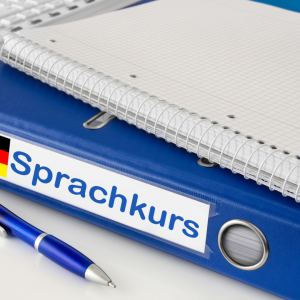 Ein Notizbuch auf einem Aktenordner. Auf dem Aktenordner steht Sprachkurs.