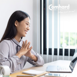 Eine Frau sitzt in einem Büro und schaut auf einen Laptop vor ihr.