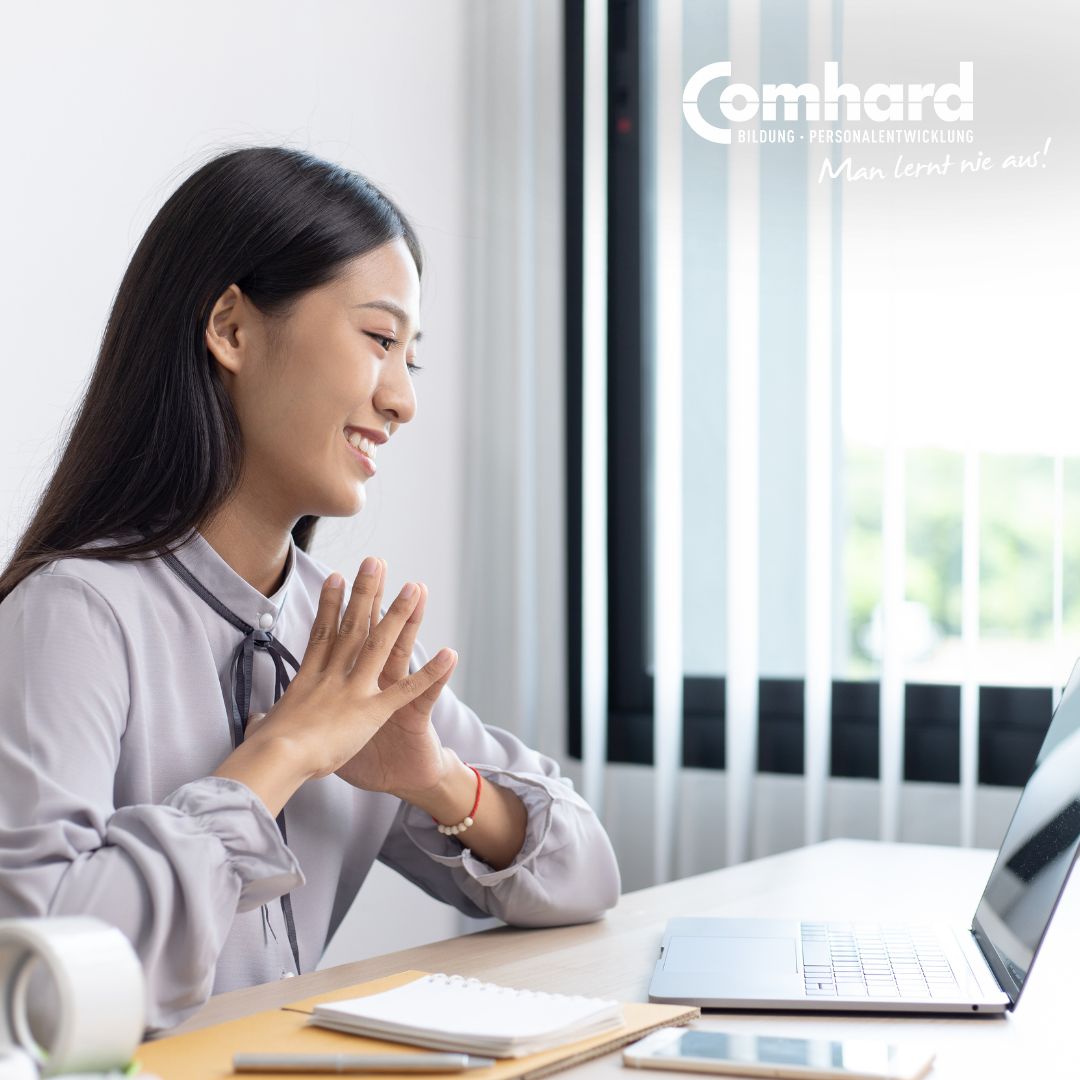 Eine Frau sitzt in einem Büro und schaut auf einen Laptop vor ihr.