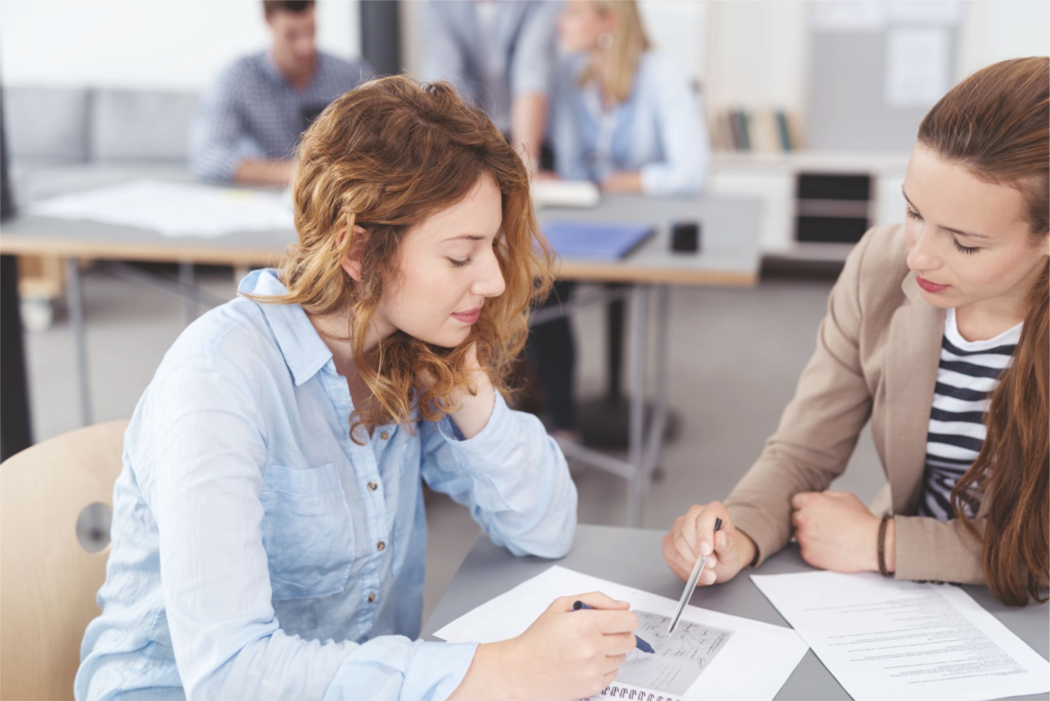 Zwei Frauen sitzen an einem Tisch und Besprechen ein Arbeitsblatt