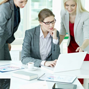 Drei Frauen schauen konzentriert auf einen Laptop.