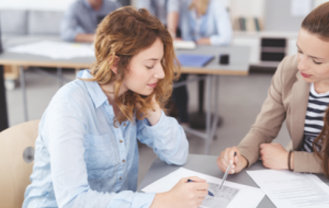 Zwei Frauen sitzen an einem Tisch und besprechen ein Dokument