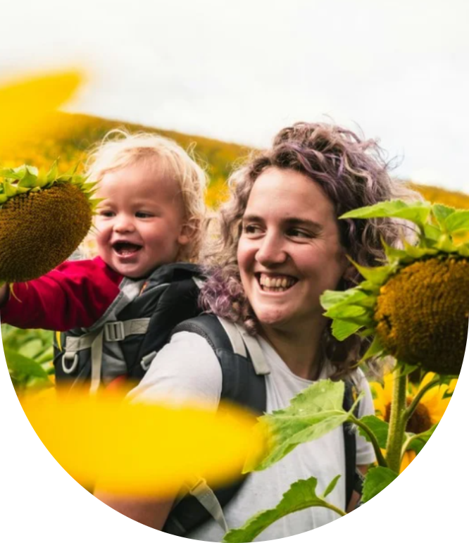 Eine Frau mit einem Kind in einem Sonnenblumenfeld.