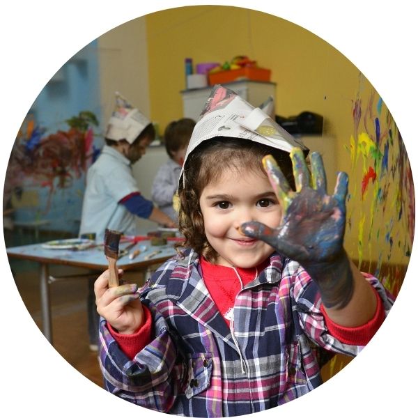 Ein Kind zeigt nach dem Fingerfarben malen die flache Hand in die Kamera.